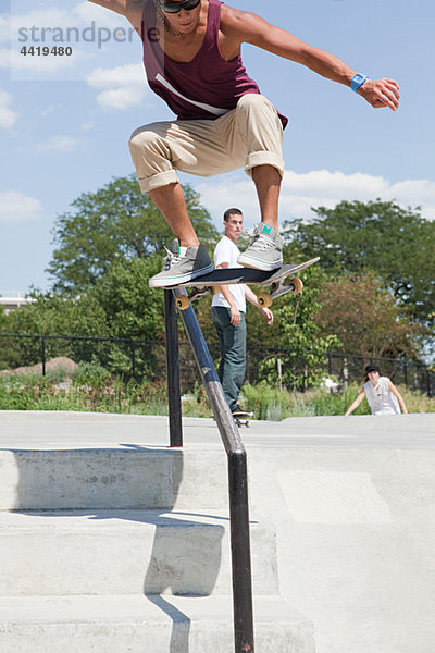 Skateboarder springt über Geländer