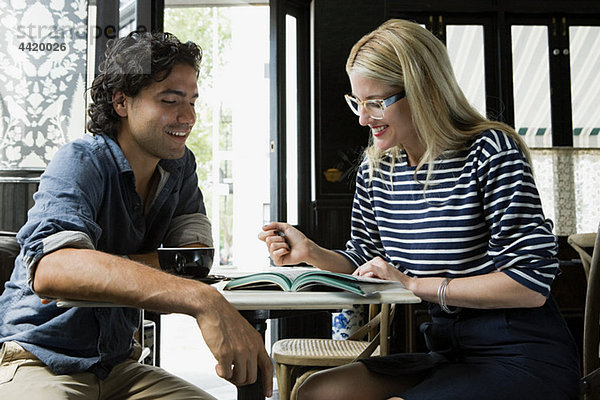 Mann mit Handy und Frau mit Laptop im Cafe