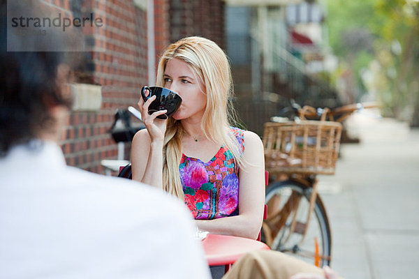 Frau trinkt Kaffee außerhalb des Cafés
