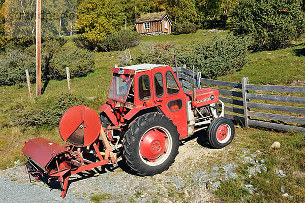 Tractor on dirt road  wooden house in the background