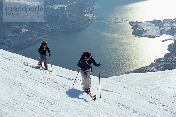 Zwei Personen Telemarkfahrer in Winterlandschaft  See Mjosa im Hintergrund