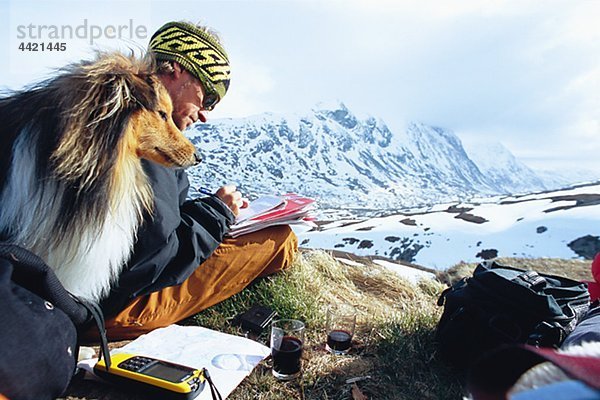 Mann mit Hund schreiben in Berglandschaft