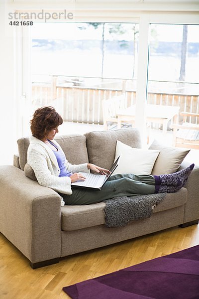 Frau sitzend auf Sofa und Surfen im internet