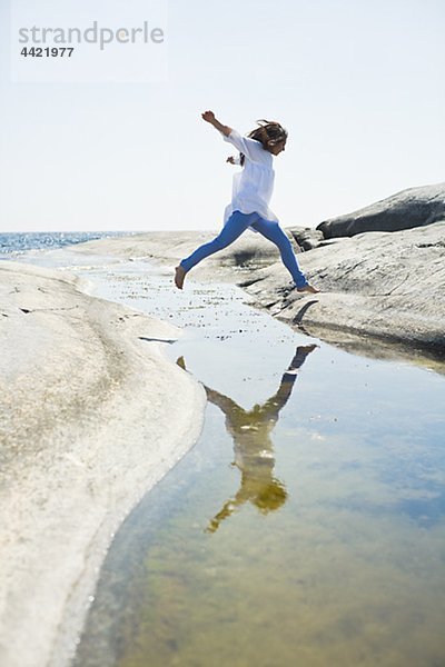 Frau springen über Wasser zu rock