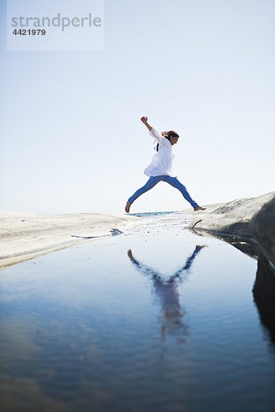 Frau springen über Wasser zu rock