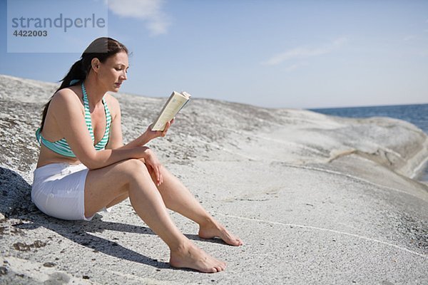 Frau sitzen auf Rock und Buch