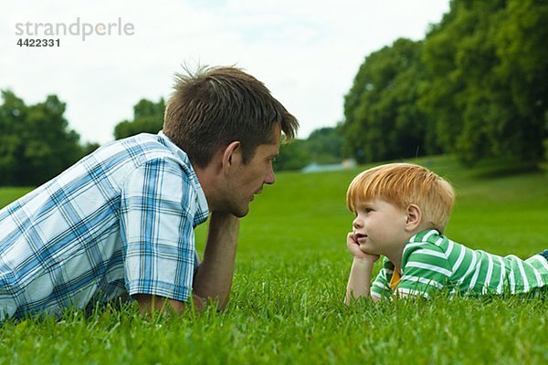Vater und Sohn auf Rasen im Park liegen