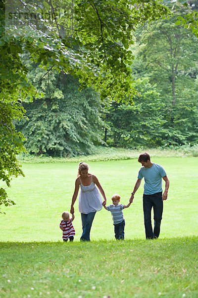 Mitte adult Paar mit Kindern im Park zu Fuß