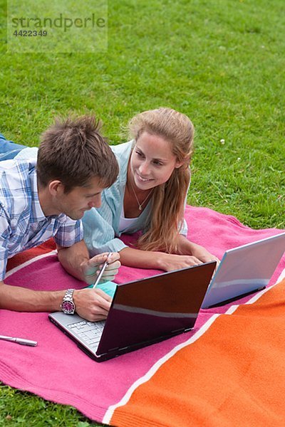 Mitte adult Paar auf Decke im Park liegen und mit laptops