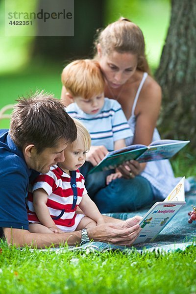 Mitte adult Eltern lesen Bücher für Kinder während Picknick