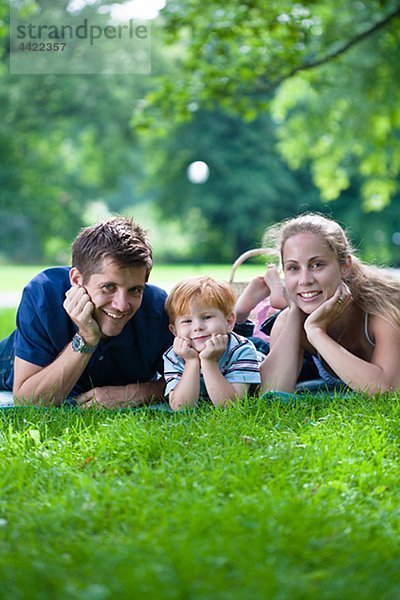 Eltern mit Sohn im Park liegen und Blick in die Kamera