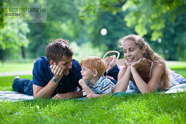 Eltern mit Sohn im Park liegen und wegsehen