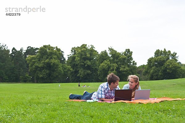 Mitte adult paar liegend auf Decke und mit laptops