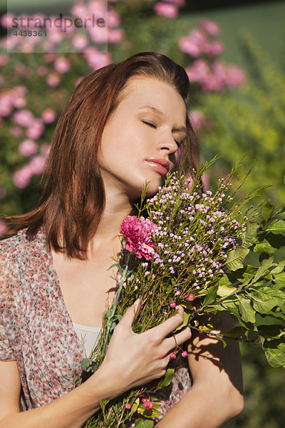 Junge Frau mit geschlossenen Augen  die einen Blumenstrauß hält.