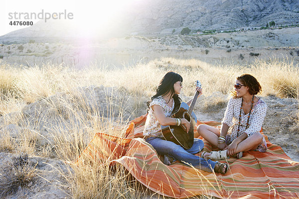 Frauen spielen Gitarre im Gras