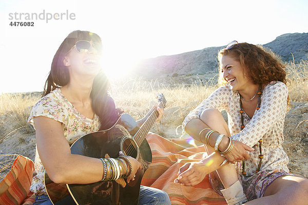 Frauen spielen Gitarre im Gras