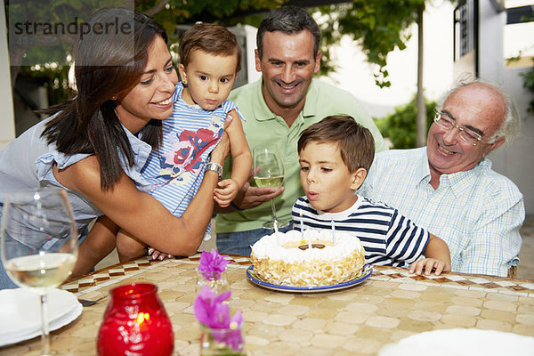 Familie bläst Kerzen auf Kuchen aus