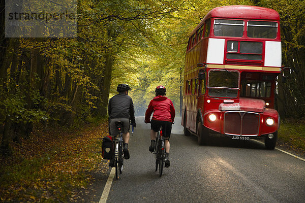 Paar Radfahren neben dem Bus auf dem Land