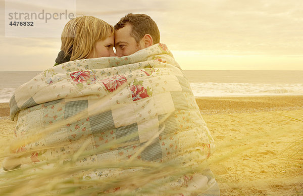 Paar Kuscheln unter der Decke am Strand