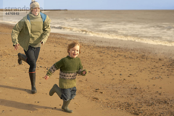 Frau  kleiner Junge  der am Strand rennt. Herbst