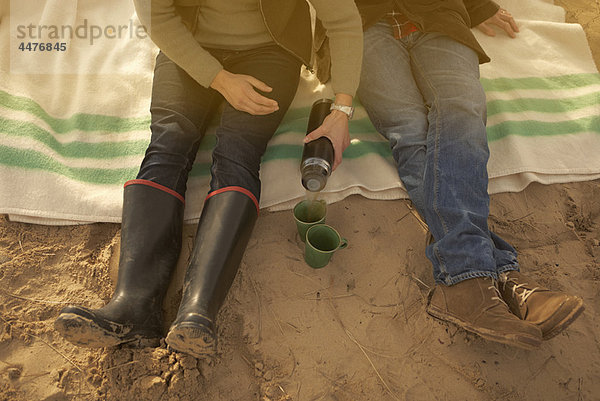 Paar am Strand bei Kaffee aus der Flasche