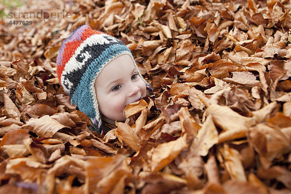 Mädchen im Herbstlaub begraben