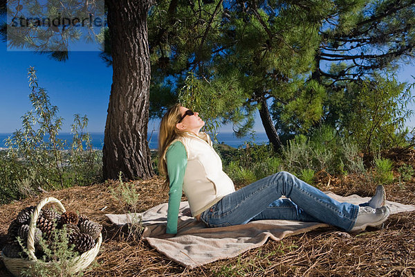 Frau auf Decke entspannt in ländlicher Umgebung