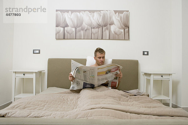 Mann  Bett  jung  Zeitung  vorlesen