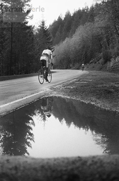 Ein Mann auf einem Rennrad  der eine Bergstraße hinauffährt.