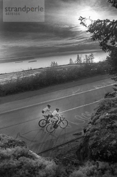 Two men riding racing bicycles  rural setting