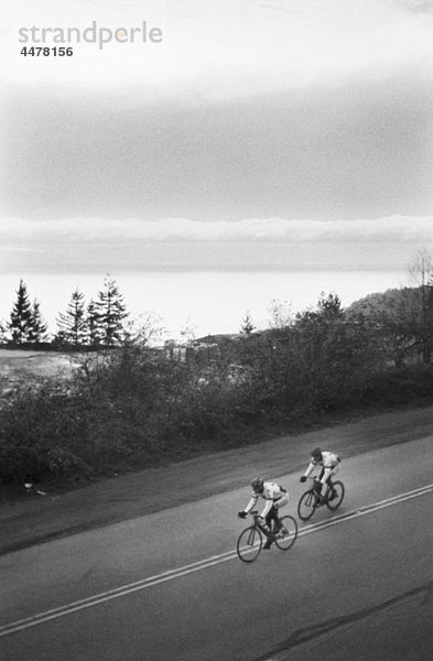 Two men riding racing bicycles  rural setting