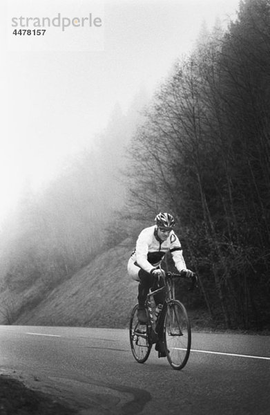 Ein Mann auf einem Rennrad  der eine Bergstraße hinauffährt.