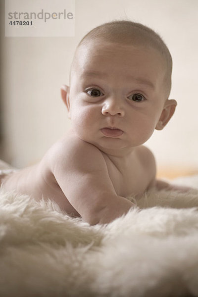 Ein Baby auf einem Teppich liegend