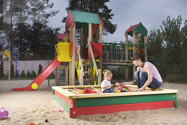 Mutter und Tochter spielen im Sandkasten.