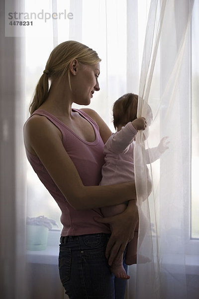 Eine Mutter und ihre kleine Tochter schauen aus dem Fenster.