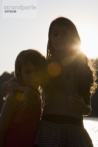 Ein Mädchen mit dem Arm um ihre kleine Schwester  Portrait