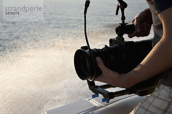 Ein Kameramann  der auf einem Motorboot filmt.