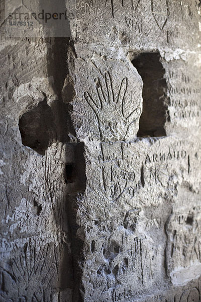 Handabdrücke und handgeschriebene Graffiti in eine Steinmauer geätzt