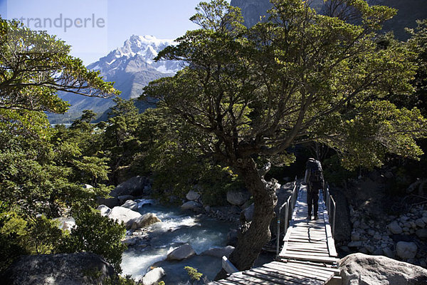 Eine Person  die beim Wandern durch die Berge einen Fluss überquert  Patagonien  Chile