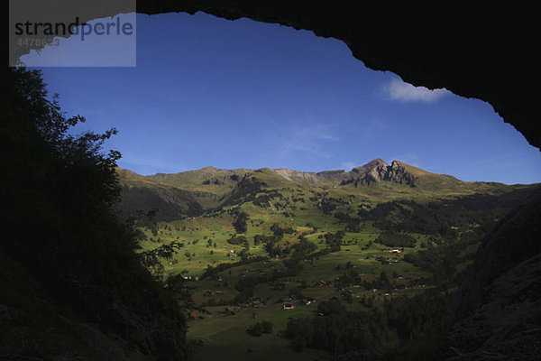 Schweizer Bauernlandschaft umrahmt von einem gewölbten Felsen