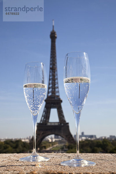 Zwei Champagnerflöten vor dem Eiffelturm  Schwerpunkt Vordergrund