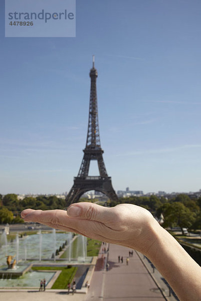 Die optische Täuschung einer Frau  die den Eiffelturm in der Hand hält.