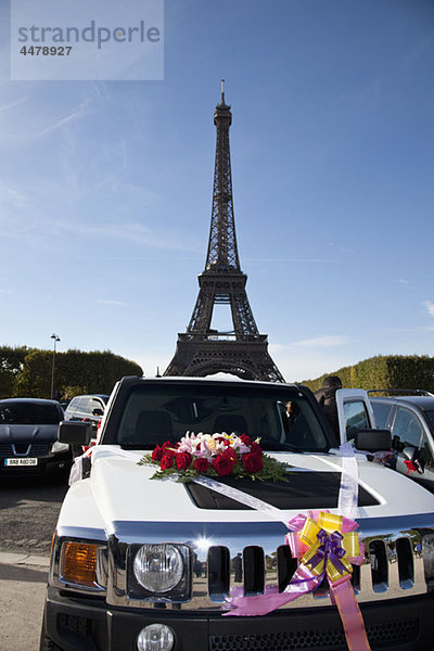 Ein mit Blumen und Bändern verziertes Auto vor dem Eiffelturm