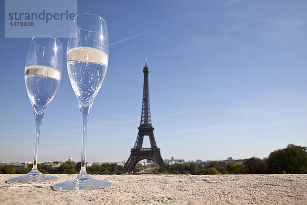 Zwei Champagnerflöten vor dem Eiffelturm  Schwerpunkt Vordergrund