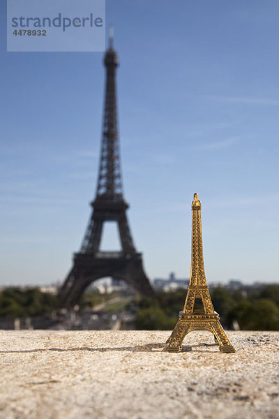 Ein Eiffelturm-Souvenir neben dem echten Eiffelturm  Schwerpunkt Vordergrund