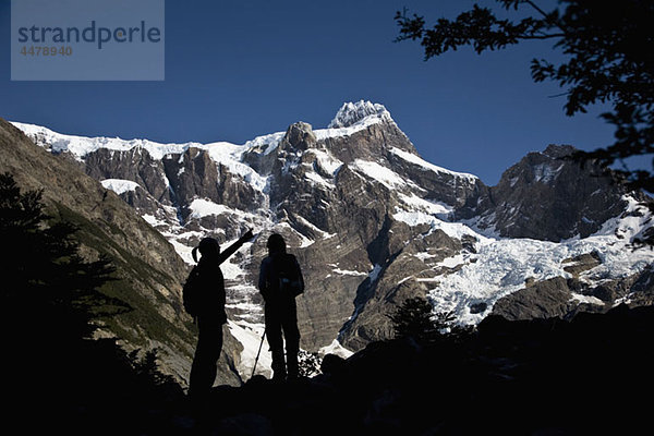 Zwei Personen in Silhouette unter verschneiten Bergen  Torres del Paine Nationalpark  Chile