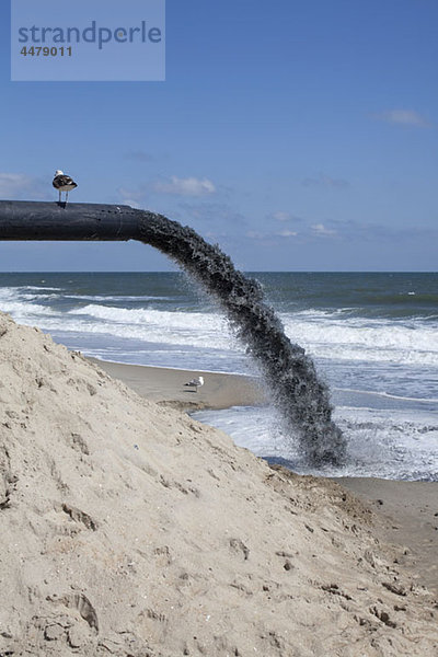Ein großes Rohr pumpt Sand an den Strand.