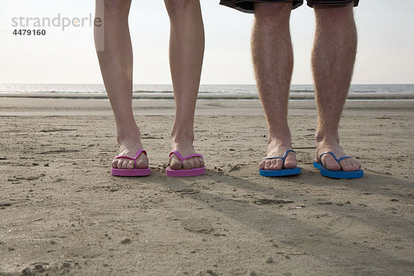 Ein junges Paar mit Flip-Flops am Strand  niedriger Abschnitt