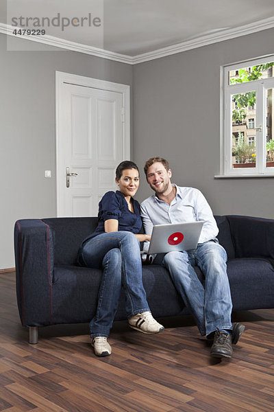 Ein junges Paar mit einem Laptop im Wohnzimmer