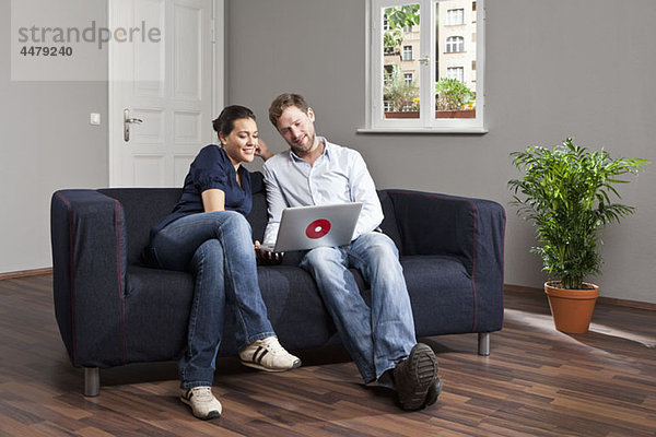 Ein junges Paar mit einem Laptop im Wohnzimmer